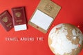 Cork globe with red pins, blank mockup calendar and passports with ticket and text `Travel around the world`