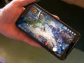 A android smartphone in the hands of a white man. Playing mobile MMORPG Black Desert Mobile. A