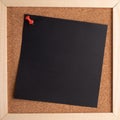 Cork note board with wooden frame with blank black square sheet for writing text. Royalty Free Stock Photo