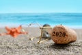 Cork stopper of champagne with number 2020 and starfish on sand beach.