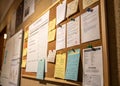 Corkboard covered with papers and notes attached with push pins in an office or home environment setting Royalty Free Stock Photo