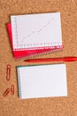 Corkboard desk with a open square paper spiral notebook and office appliances. Billboard table with different sizes and