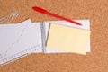 Corkboard desk with a open square paper spiral notebook and office appliances. Billboard table with different sizes and