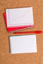 Corkboard desk with a open square paper spiral notebook and office appliances. Billboard table with different sizes and