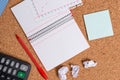 Corkboard desk with a open square paper spiral notebook and office appliances. Billboard table with different sizes and