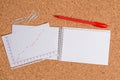Corkboard desk with a open square paper spiral notebook and office appliances. Billboard table with different sizes and