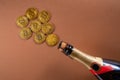 Corked bottle of champagne and golden bitcoins on brown studio background. Cryptocurrency gold coins, virtual cash and Royalty Free Stock Photo