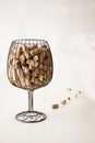 Corks from the bottles inside a vase simulating a glass of wine and some cork stoppers next to the vase with a white background