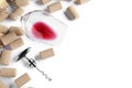 Corkscrew, glass with red wine and stoppers on white background, top view