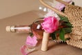 Corkscrew near wicker bag with bottle of rose wine and beautiful pink peonies on brown background, closeup Royalty Free Stock Photo