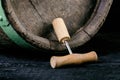 Corkscrew next to a wooden wine barrel. Wine on a wooden barrel. Burnt, black wooden background. Vintage. Copyspace for a text. Gr Royalty Free Stock Photo