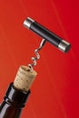 Corkscrew and wine bottle over red background Royalty Free Stock Photo
