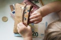 Corkwood wallet and baby hands touching money on a white background. Ten, twenty and fifty euro bills and some coins. Royalty Free Stock Photo