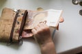 Corkwood wallet and baby hands touching money on a white background. Ten, twenty and fifty euro bills and some coins. Royalty Free Stock Photo