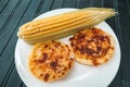 Corn arepas next to an ear of corn