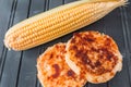 Corn arepas next to an ear of corn.