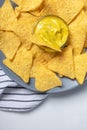 Corn chips with cheese sauce on gray plate and striped napkin on white table, top view. Mexican food photo, vertical. Nachos Royalty Free Stock Photo