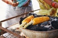 Corn cobs on the grill. Close-up image with corns and hands. Asian, Indian and Chinese street food. Trolley on the beach Royalty Free Stock Photo