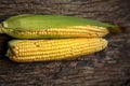 Corn cobs lie on a wooden table. Ripe corn lies on a textured old table. Royalty Free Stock Photo