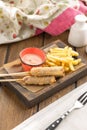 Corn dog sausage on a stick with french fries on wooden table Royalty Free Stock Photo