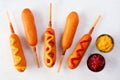 Corn dogs with a variety of toppings over white marble