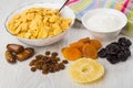 Corn flakes in bowl, sour cream, heaps of dried fruits Royalty Free Stock Photo