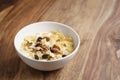 Corn flakes with fruits and nuts in white bowl on wood table with copy space Royalty Free Stock Photo