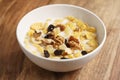 Corn flakes with fruits and nuts in white bowl on wood table Royalty Free Stock Photo