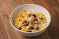 Corn flakes with nuts and fruits in white bowl on wood table Royalty Free Stock Photo