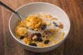 Corn flakes with nuts and fruits in white bowl on wood table Royalty Free Stock Photo