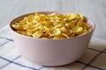 Corn flakes in a pink bowl for breakfast over white wooden surface, side view Royalty Free Stock Photo