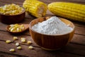 Corn flour in wooden bowl and corn cobs on table