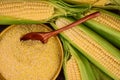 Corn grits in a bowl against a background of fresh corn on the cob. The concept of producing cereals from grains, corn products. Royalty Free Stock Photo