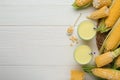 Corn juice and cobs on white wooden table, flat lay. Space for text Royalty Free Stock Photo