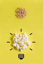 Corn kernels and popcorn with light bulb drawing on yellow background