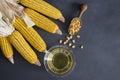 Corn oil in glass bowl with dried corn groats and kernels on rustic backdro