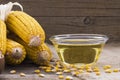 Corn oil in glass bowl with dried corn groats and kernels on rustic backdro Royalty Free Stock Photo