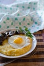 Corn porridge, fried egg, fried mushrooms with onions in a plate on a wicker bamboo napkin