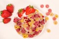 Corn rings with milk in a plate with berries and fruits, viewed from above on a white background. The concept of quick Royalty Free Stock Photo