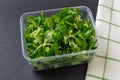 Corn salad leaves or mache in a plastic food container on a black backgrond. Lambs lettuce for vitamin vegetable salads. Low Royalty Free Stock Photo