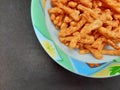 corn spicy sticks snacks in bowl isolated on black background