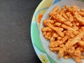 corn spicy sticks snacks in bowl isolated on black background