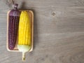 The corn stalks boiled and delicious on the wooden dish and the dish on wooden table. The color of corn is yellow and brown. copy Royalty Free Stock Photo