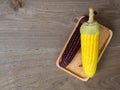 The corn stalks boiled and delicious on the wooden dish and the dish on wooden table. The color of corn is yellow and brown. copy Royalty Free Stock Photo