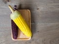 The corn stalks boiled and delicious on the wooden dish and the dish on wooden table. The color of corn is yellow and brown. copy Royalty Free Stock Photo