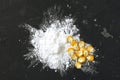 Corn starch with yellow grains on a black background, top view. Corn white starch and yellow kernels on the table Royalty Free Stock Photo