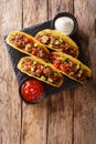 Corn tacos filled with minced beef and vegetables served with sauces close-up. Vertical top view Royalty Free Stock Photo