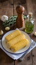 Corn on white plate with herbs, rustic kitchen setting Royalty Free Stock Photo