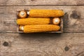 Corn in wooden box on old shabby grungy rustic wooden background, flat lay