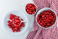 Cornel berries in different plates on a white and picnic cloth background. flat lay